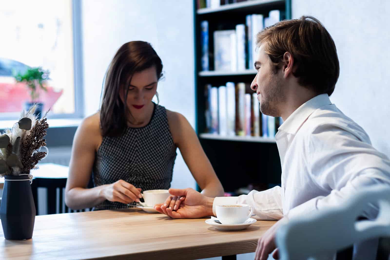 par på ett kafé vid ett bord dricker kaffe som ler mot varandra