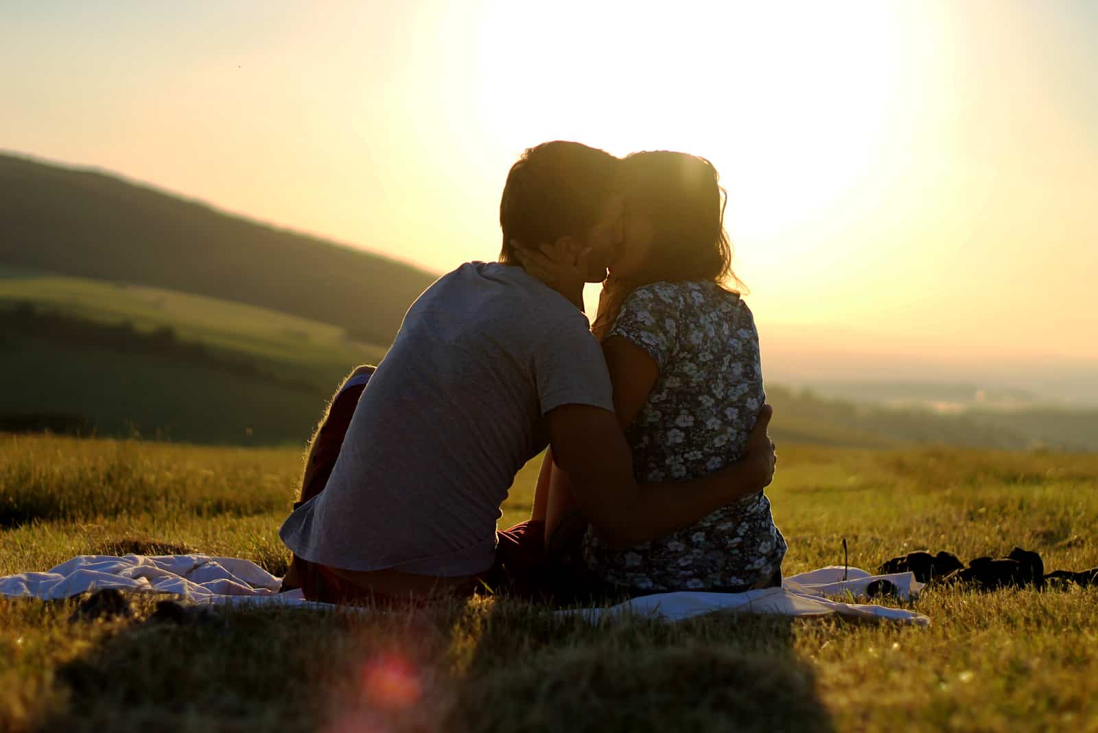par sitter på gräs kyssar