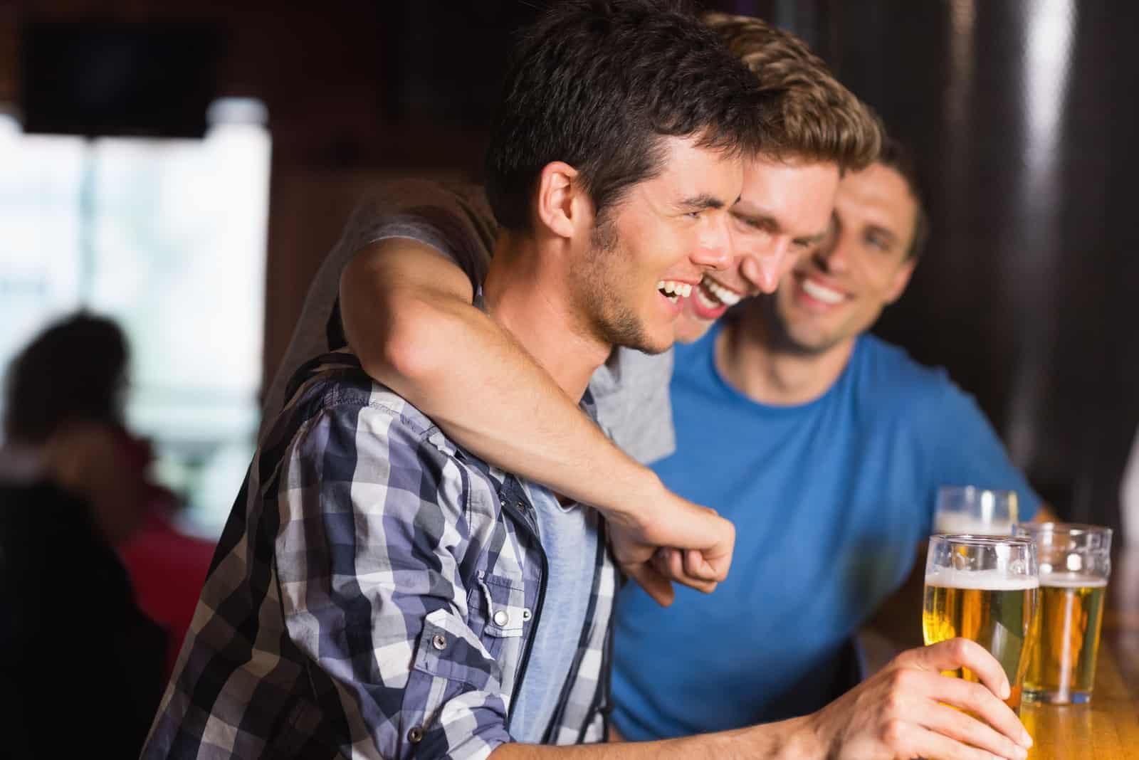 Lyckliga vänner som hamnar över pints i en bar