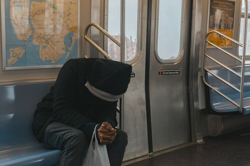 person i svart hoodie som sitter på tågbänken
