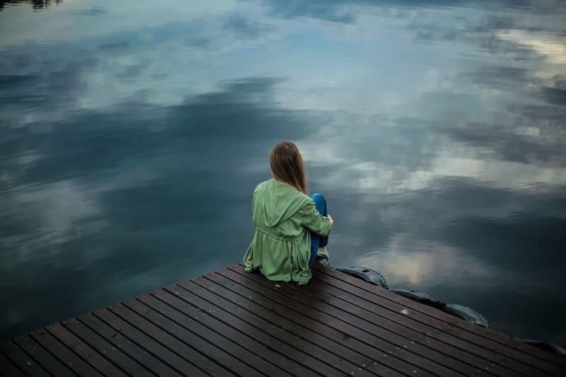 ensam kvinna som sitter vid sjön
