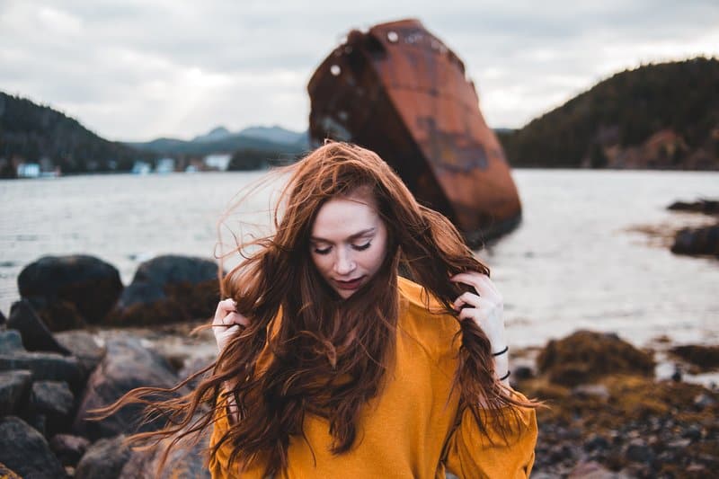 foto av kvinna som bär orange tröja medan du håller håret