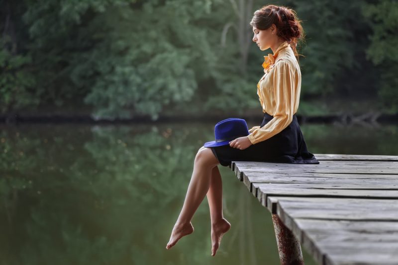 flicka sitter vid floden