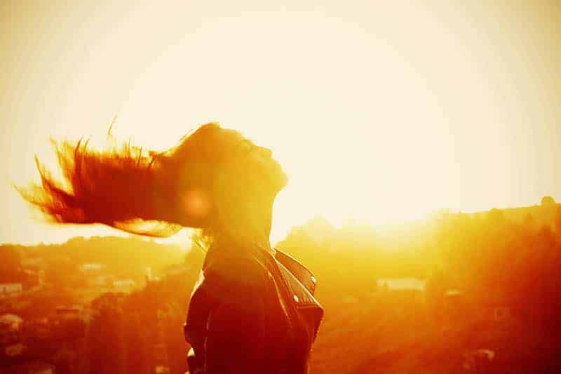 kvinnans hår som flyger på vinden i solnedgången