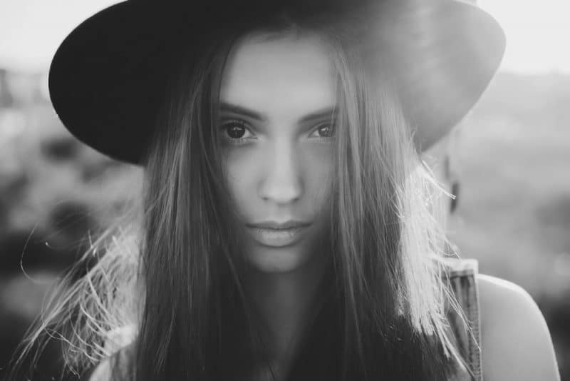 vacker ung flicka i en svart hatt poserar på gatan och ledsen