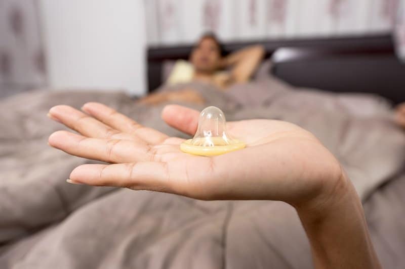 närbild foto av kvinna håller kondom