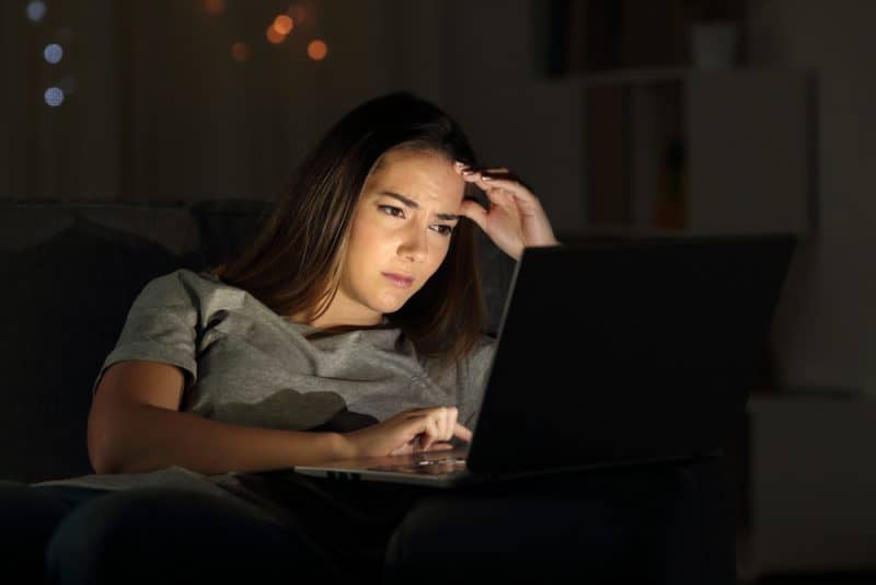orolig kvinna som använder en bärbar dator på natten hemma