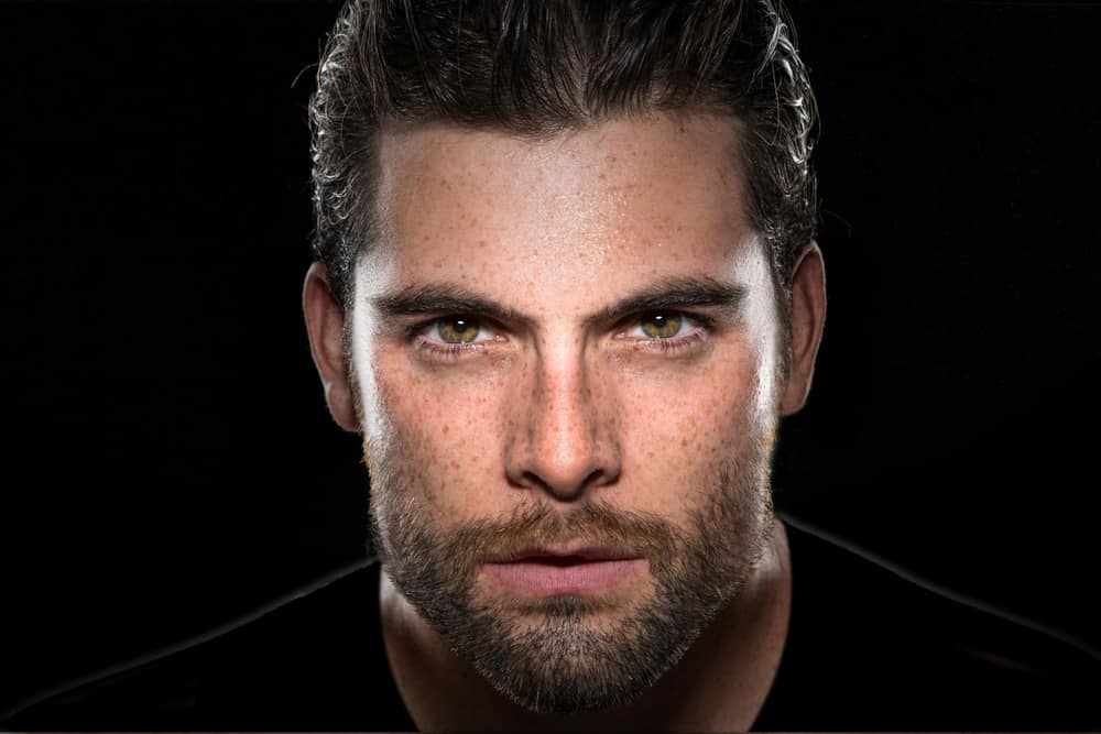 Stilig manlig modell med maskulin ansiktshår och intensiva ögon