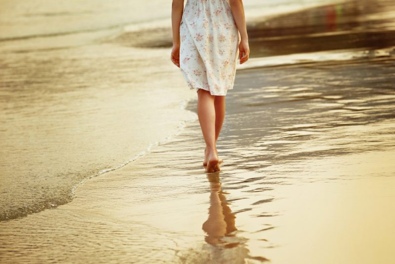 kvinna som går på stranden