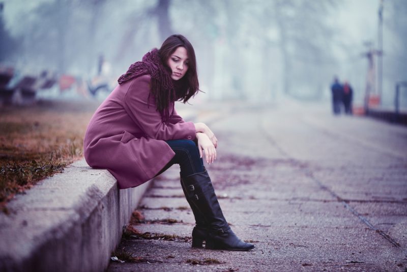 ensam ung kvinna som sitter utomhus