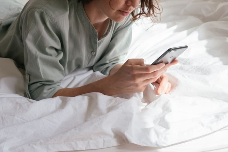 kvinna med smartphone i sin säng