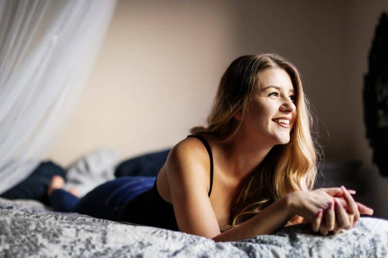 kvinna som ler liggande på sängen