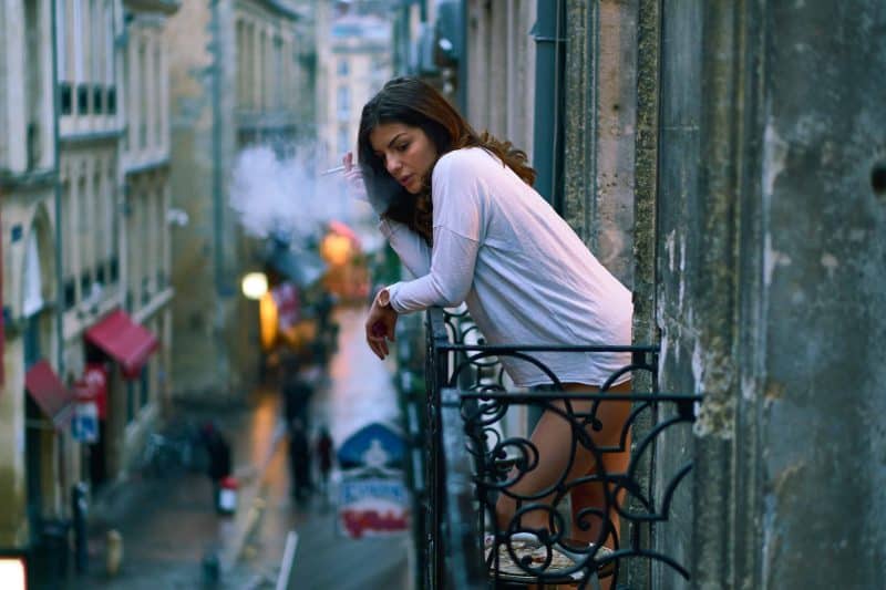 kvinna som röker cigarett på en balkong