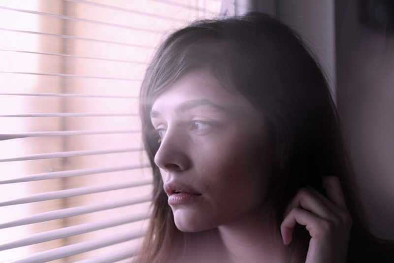 ung kvinna tittar genom fönstret