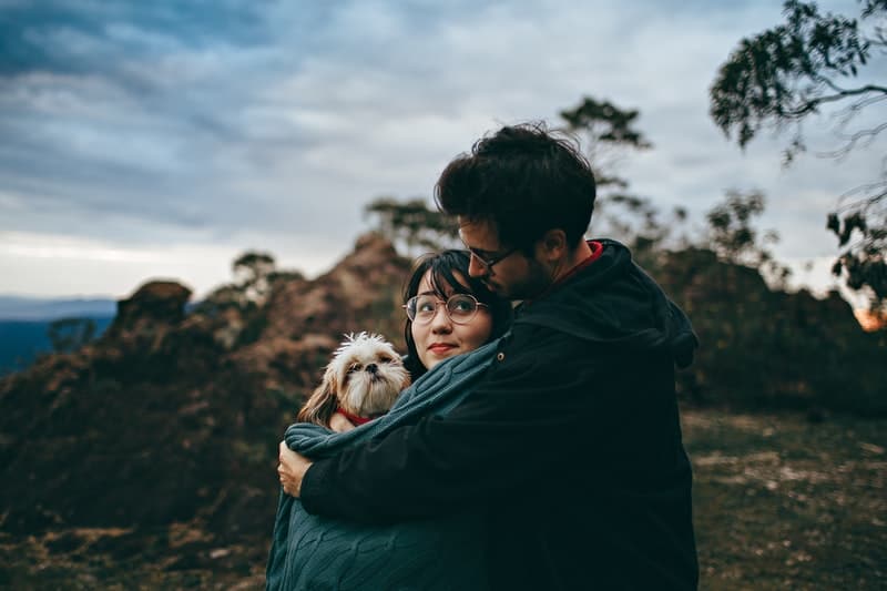 man som kramar kvinna, kvinna som håller hund