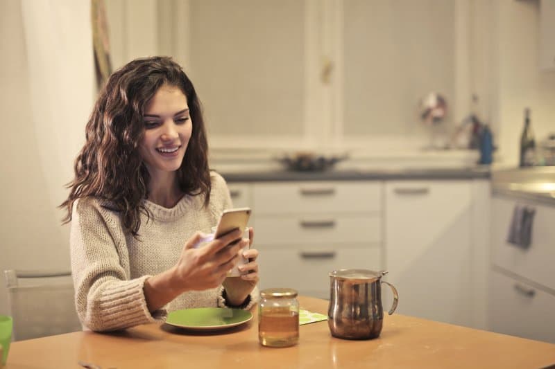 ung kvinna som dricker te och använder sin smartphone