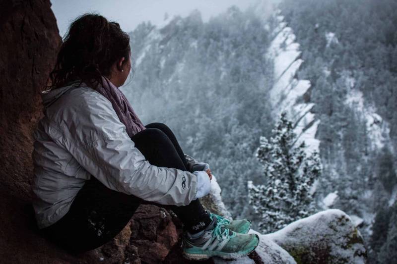 kvinna som sitter på en kulle på vinterdagen och ser nackdelen