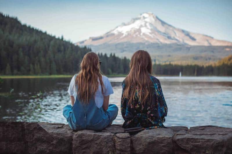 två kvinnor som sitter nära sjön