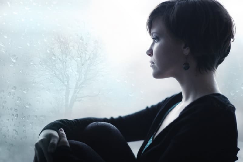 korthårig kvinna sitter och tittar ut genom fönstret