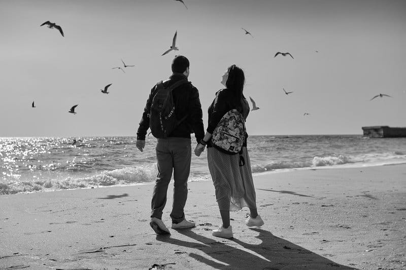 man och kvinna som går på stranden medan de håller händerna