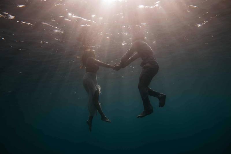 man och kvinna som håller händerna under vattnet