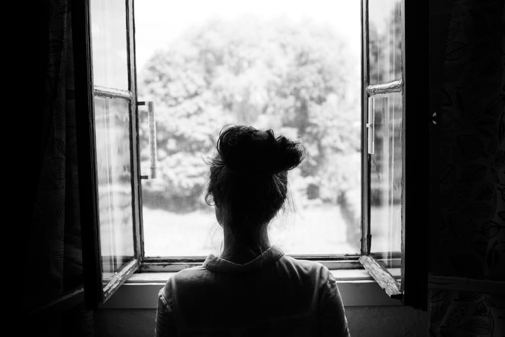 Kvinna som ser genom det gamla fönstret