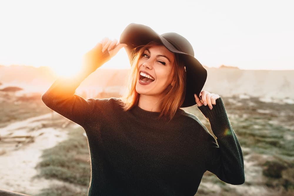 glad kvinna med hatt i solnedgången