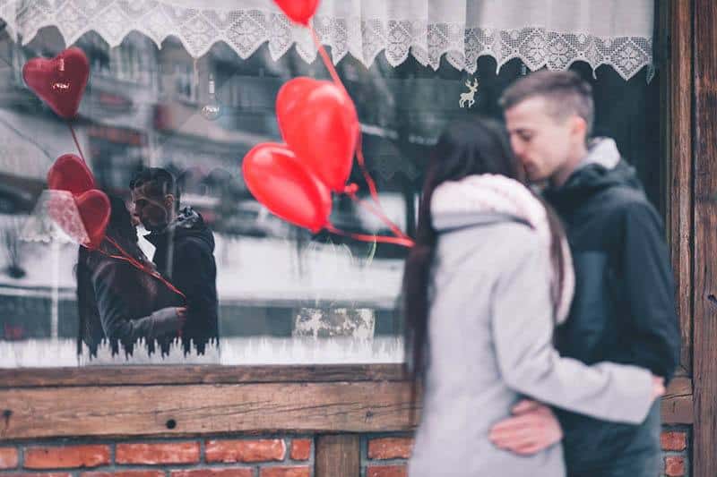 man och kvinna kysser medan du håller ballonger
