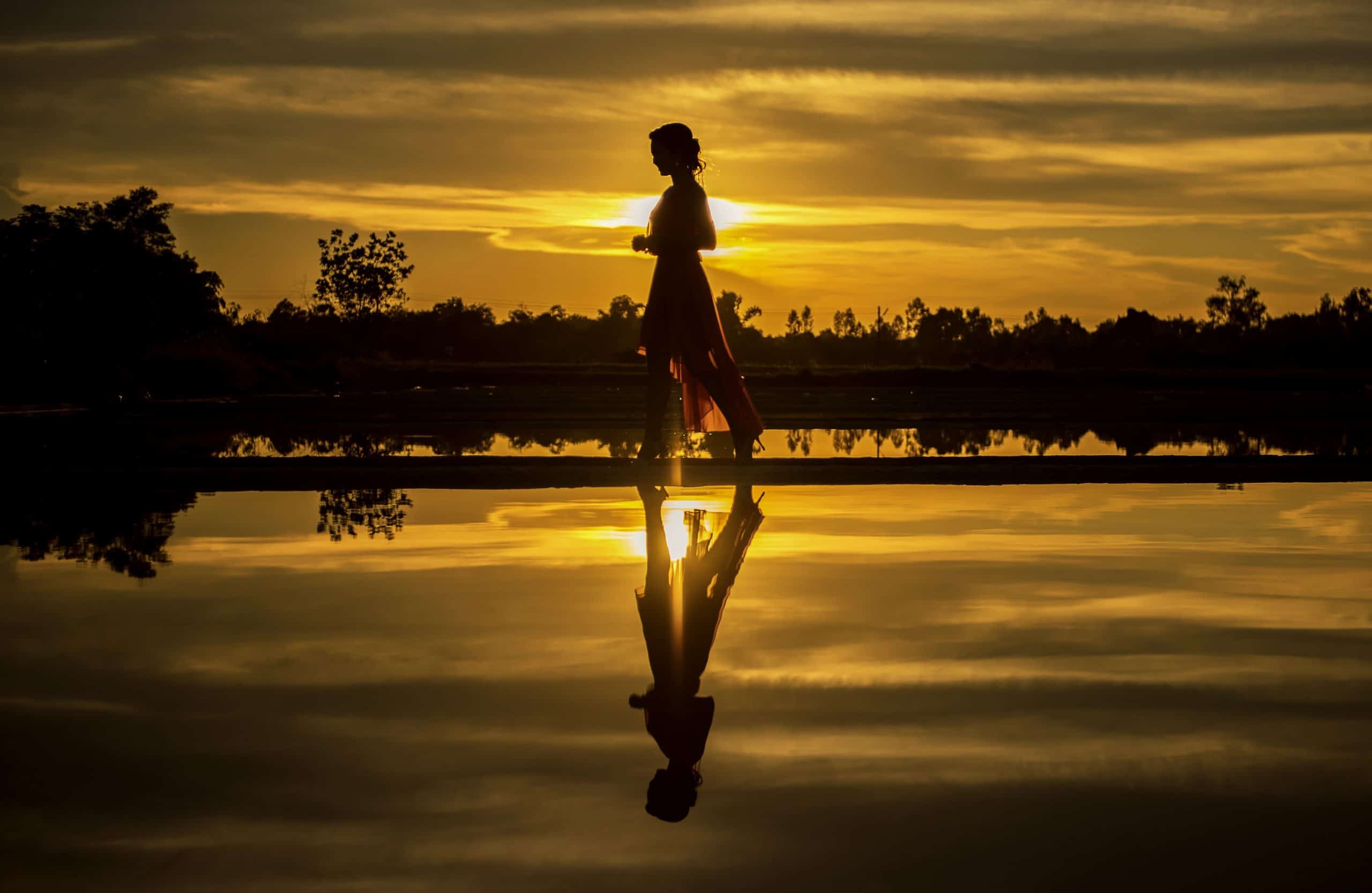 kvinna som går i solnedgång nära vatten