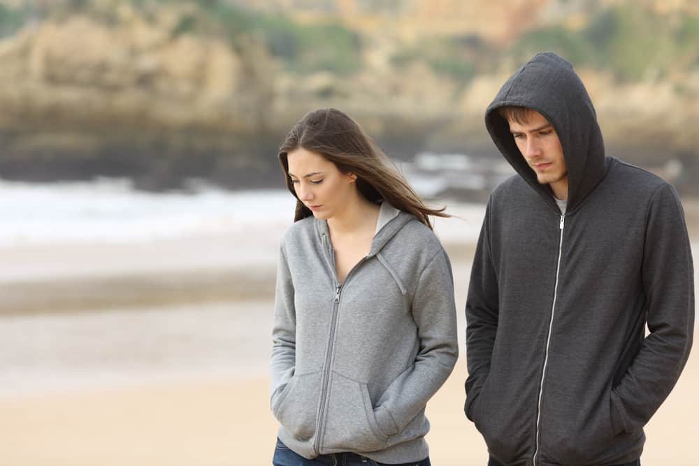 Par arga och ledsna tonåringar som tillsammans går på stranden