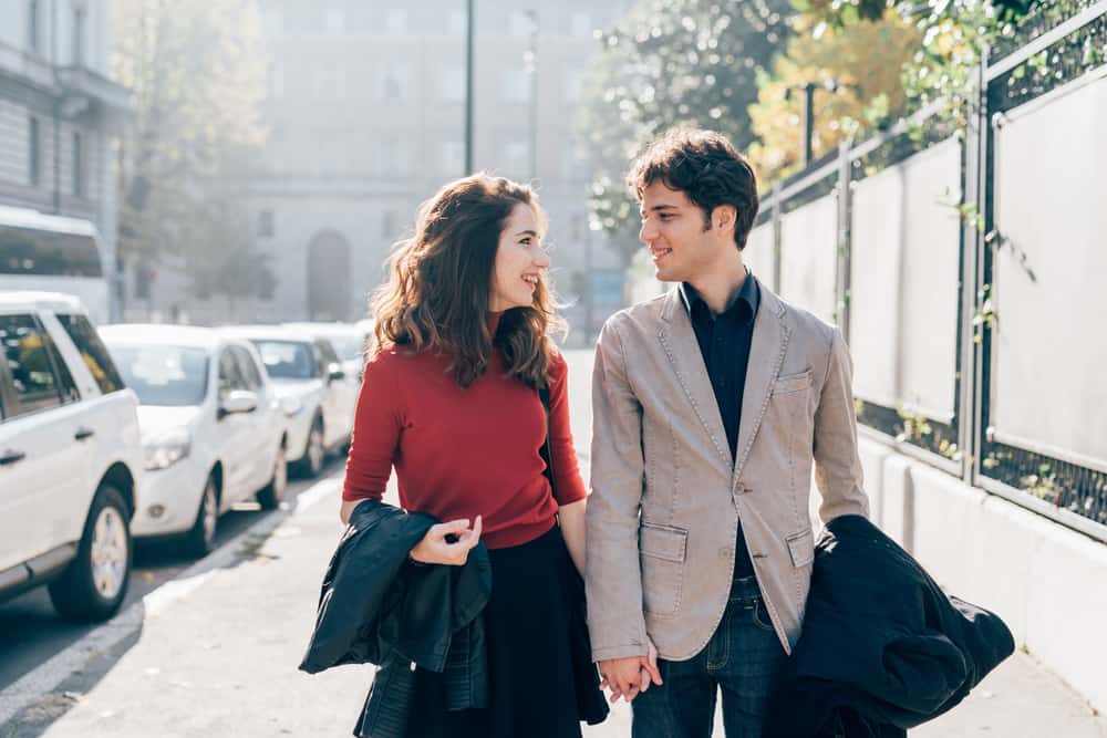 Unga härliga par som är förälskade och pratar som går utomhus i staden
