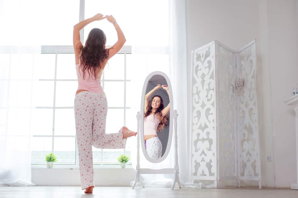 attraktiv ung kvinna som dansar i spegeln på hennes lägenhet