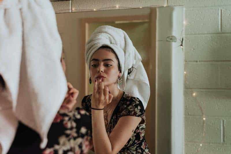 kvinna som sätter makeup framför spegeln