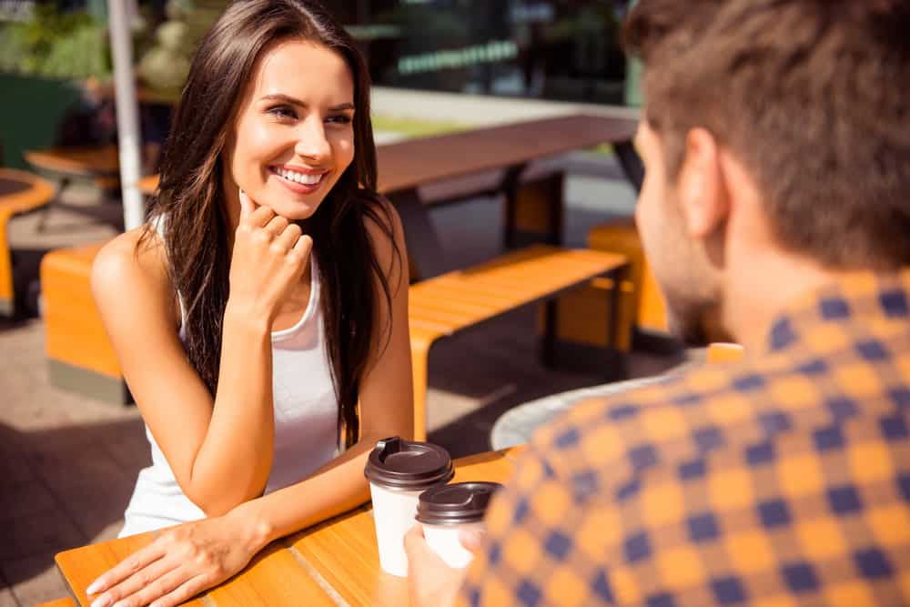leende kvinna som tittar på mannen på kaffedatum