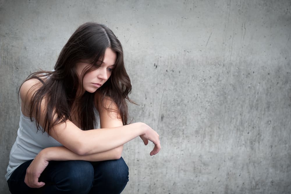tonårsflicka ser fundersam om problem framför en grå vägg
