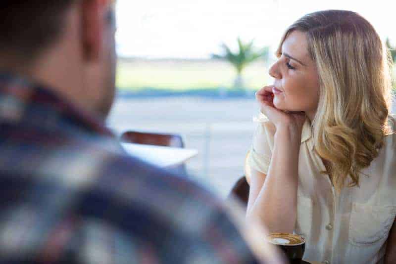 upprörd kvinna som tittar bort medan man sitter med mannen