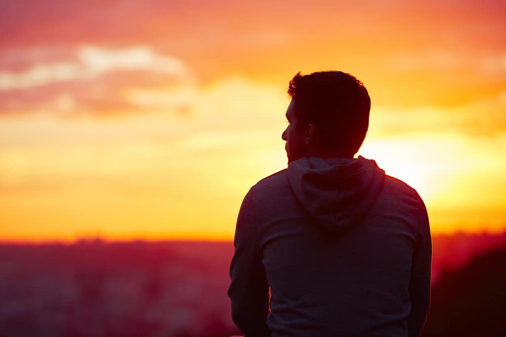 Den unga mannen tittar på soluppgången