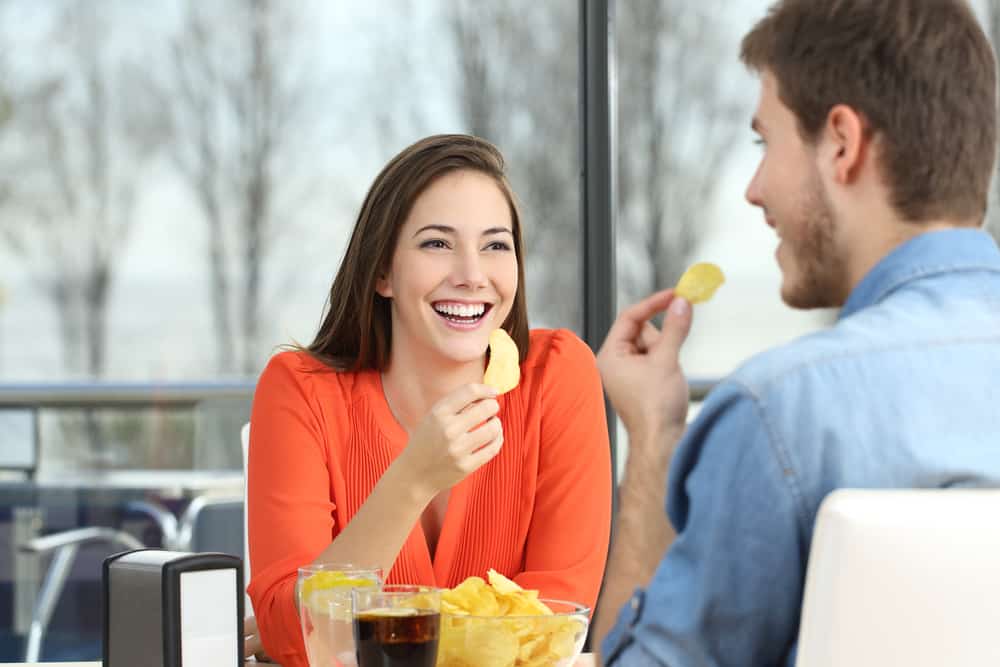 Gladlynt par som pratar och äter chippotatis som ser varandra
