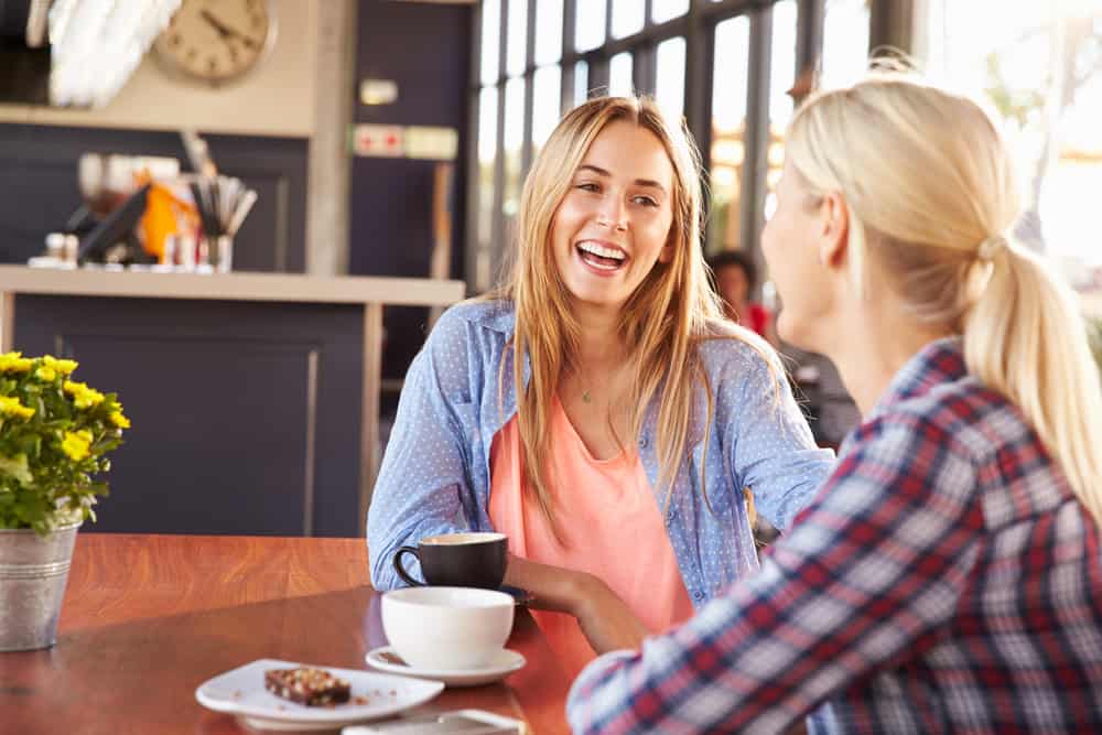 Två kvinnliga vänner som pratar på ett kafé