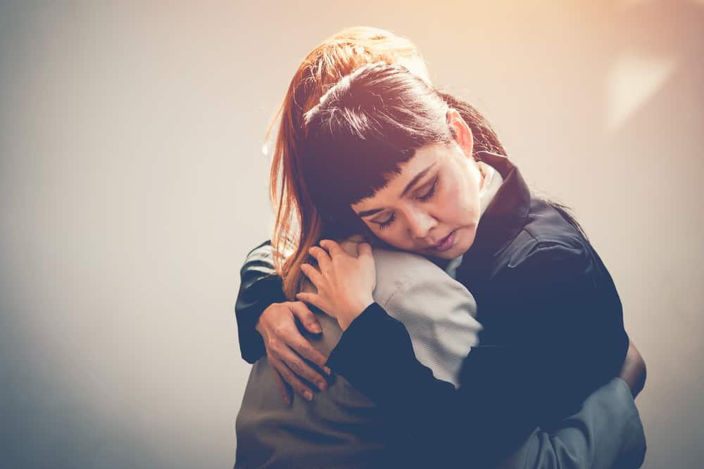 Två kvinnor kramar för att trösta