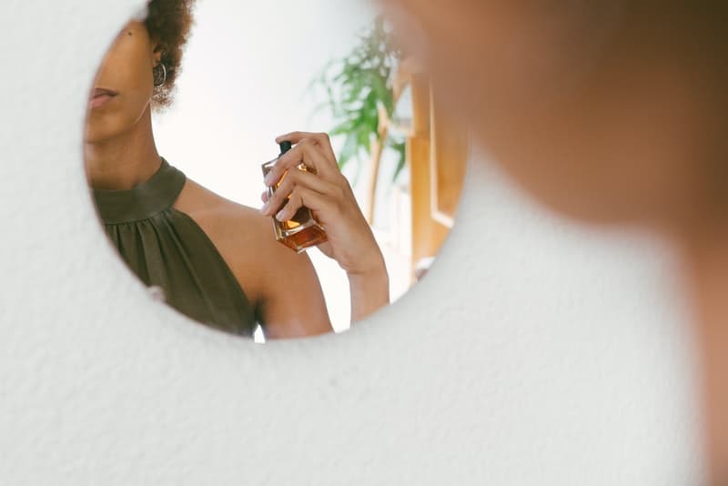 den svarta kvinnan parfymeras framför spegeln