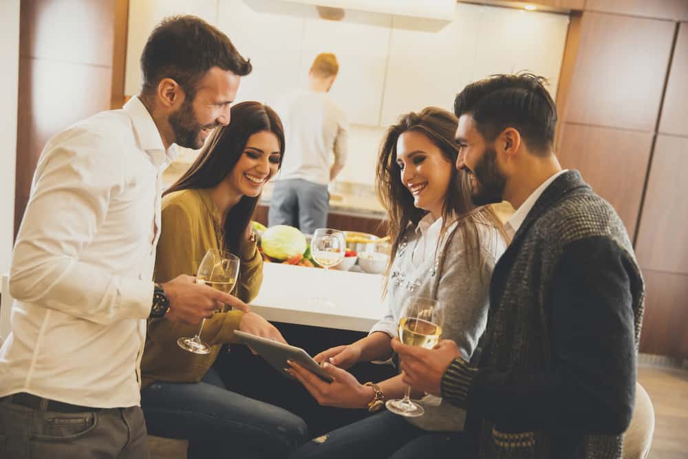 en grupp vänner dricker vitt vin i köket