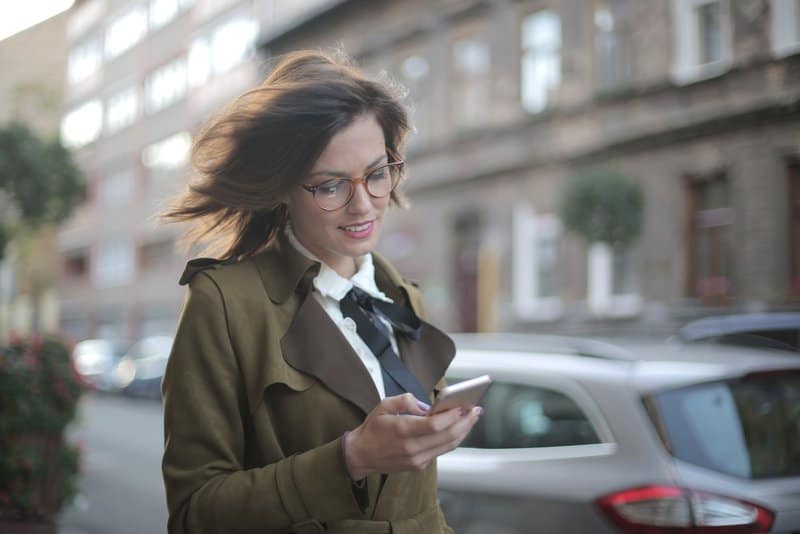 en kvinna går ner på gatan med en telefon i handen