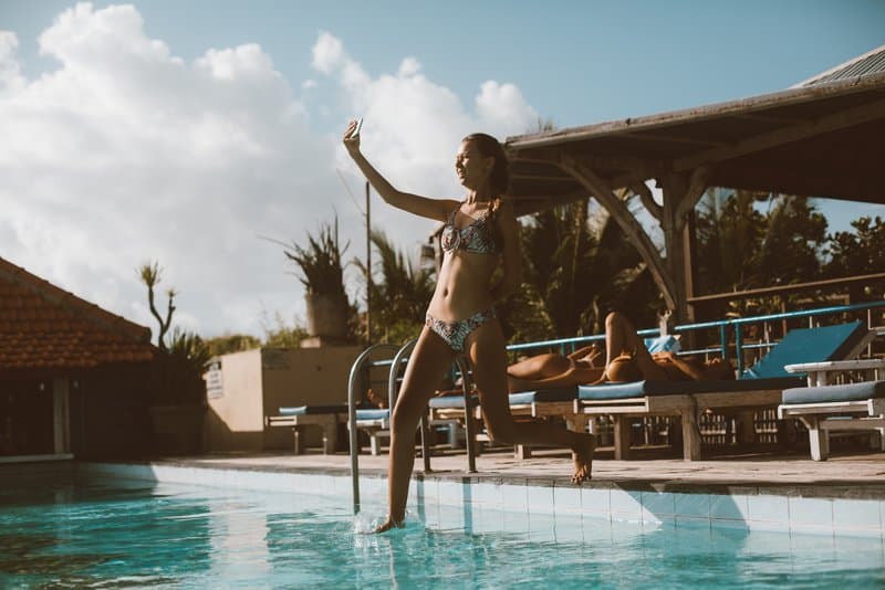 en kvinna tar ett selfiefoto när hon hoppar i poolen