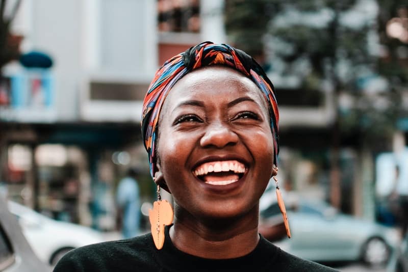 en leende svart kvinna står på gatan