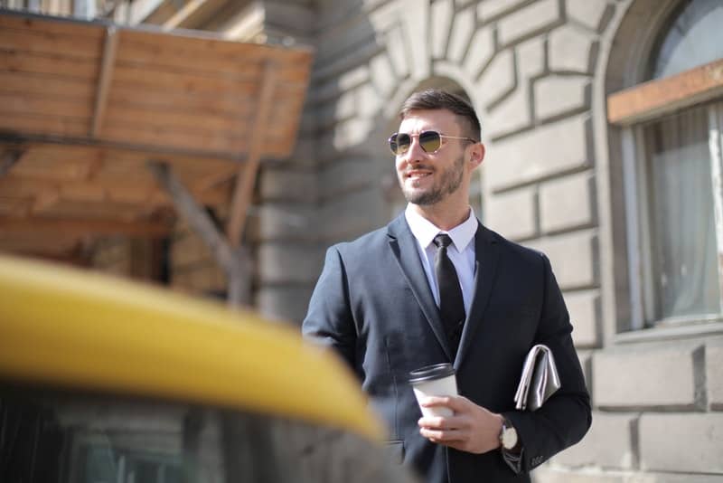 en lycklig affärsman i en avdelning som står med en kopp kaffe i handen
