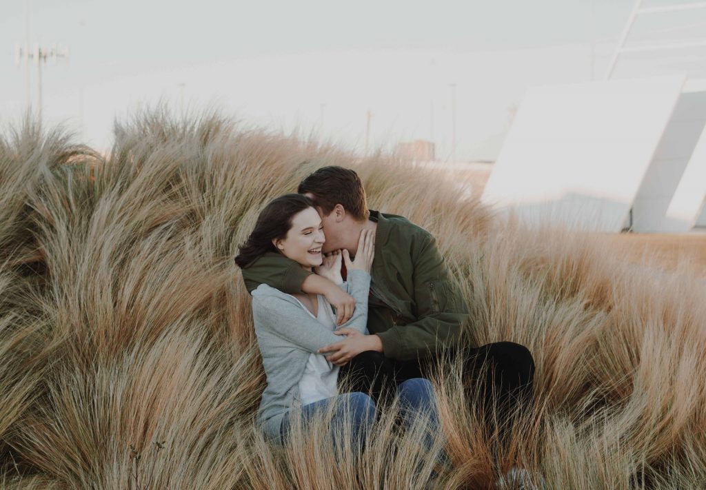 en man kysser en kvinna i ett fält