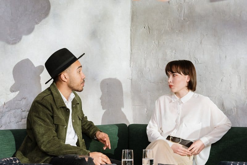 en man med hatt och en kvinna som sitter och dricker kaffe på ett kafé