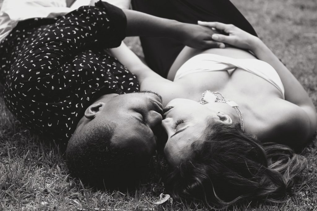 en man och en kvinna ligger i gräset och rör vid deras läppar