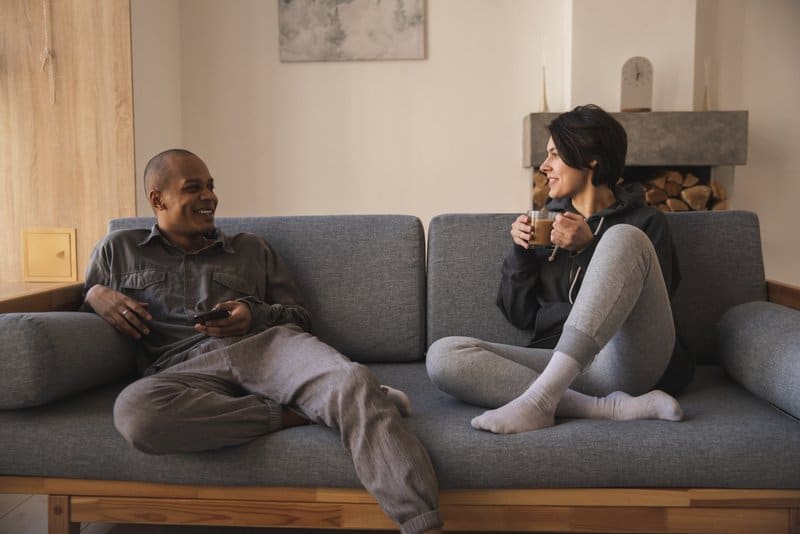 en man och en kvinna som sitter på en soffa och dricker kaffe